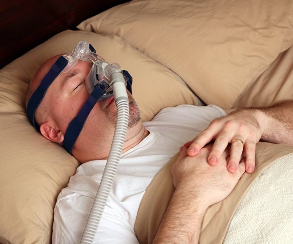 man sleeping in bed wearing a cpap