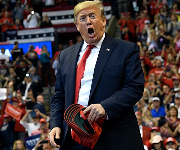 president donald trump exults while throwing out maga hats at a florida campaign rally