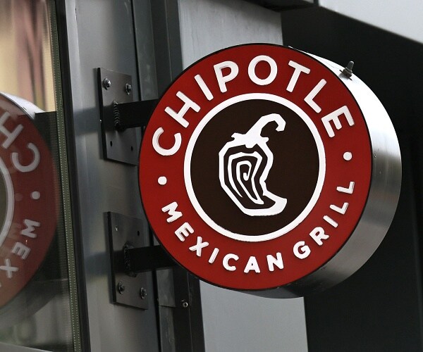 chipotle sign hangs on brick wall