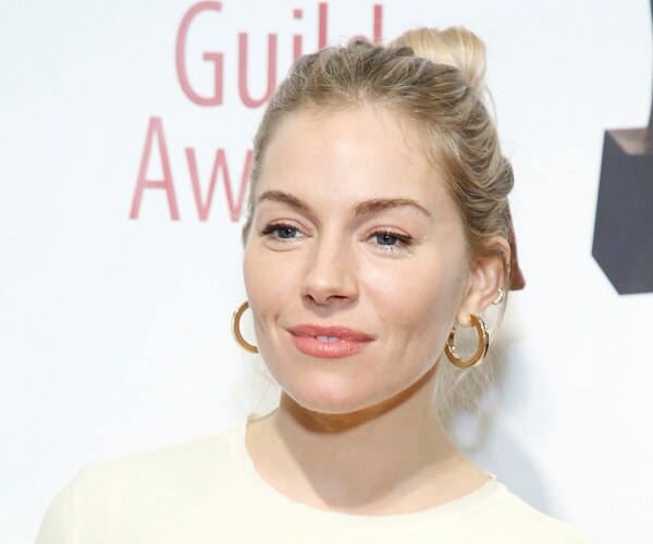 sienna miller stands on red carpet