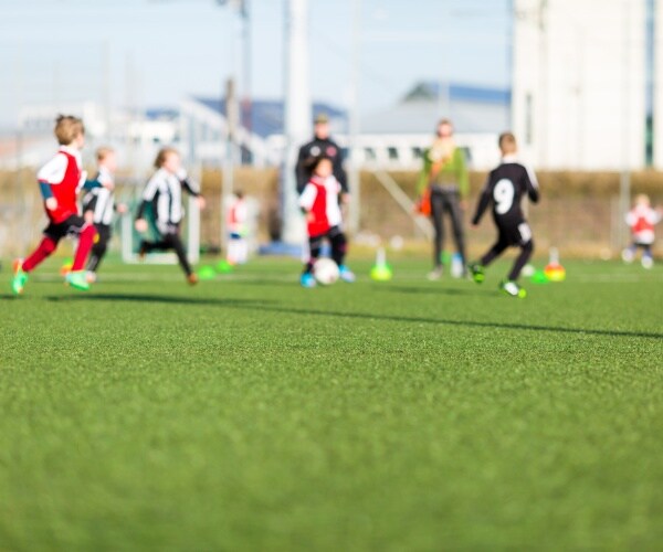 young kids playing soccer on artificial turf field