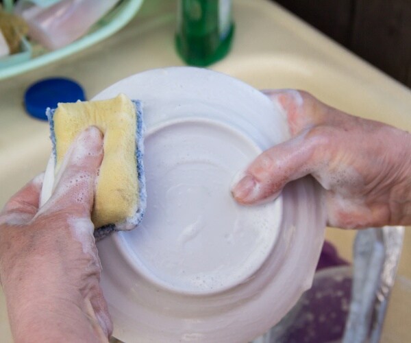 older woman's hands washing dishes