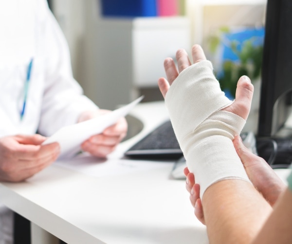 man with bandaged hand talking to doctor