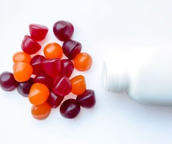 cannabis edible gummies spilling out of white container