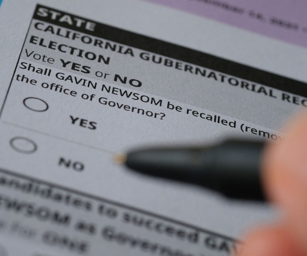 person holds pen over california recall form