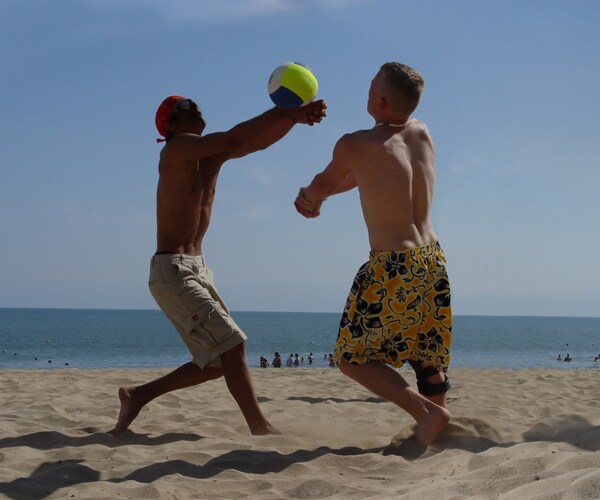 two men playing volleyball on a beach