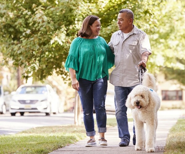 couple walking dog in suburban street