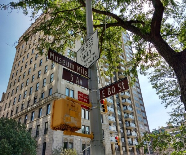 museum mile street marker is shown in front of a tree and building