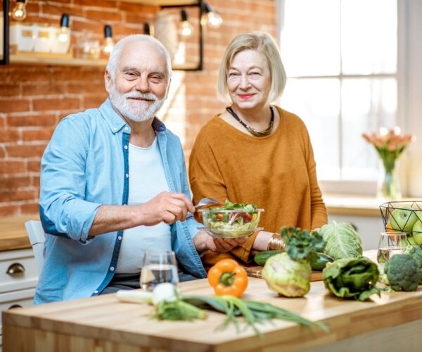 older man and woman in kitchen making a vegetarian meal