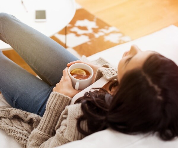 woman relaxing on couch with cup of tea