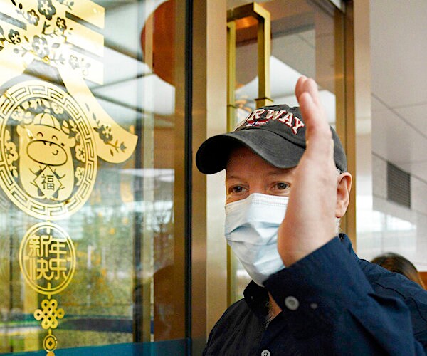 a man raises his left hand in front of a painted glass window in china