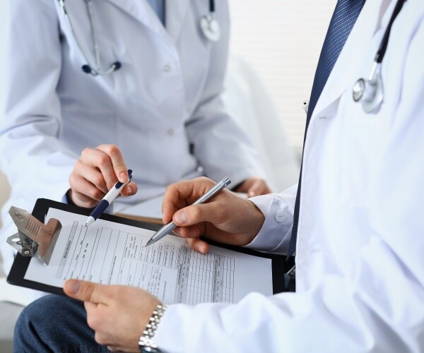 two doctors talking and filling out paperwork