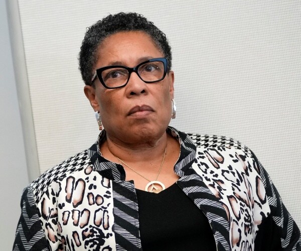 marcia fudge stands against a wall and listens