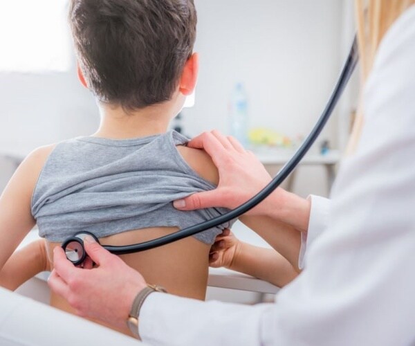 doctor listening to lungs of young boy with stethoscope