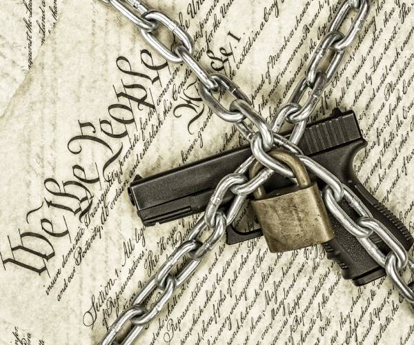 a pistol chained and locked on top of the united states constitution