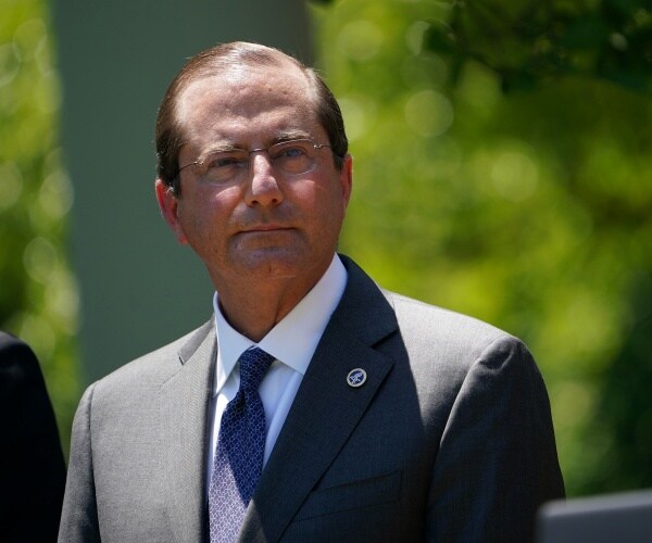 azar standing outside in the sunlight in a suit and blue tie