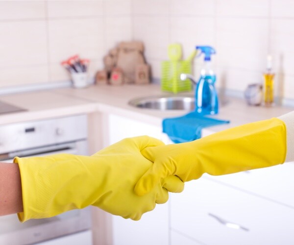 two hands in yellow cleaning gloves shaking hands