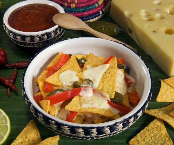 a bowl of nachos is shown beside limes and salsa