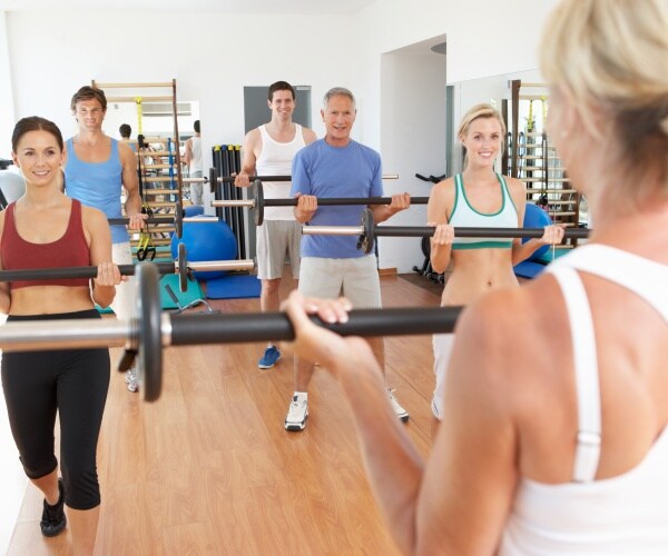 men and women lifting weights in a group class