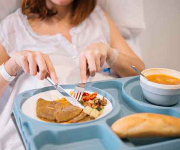 image of woman eating food in hospital bed