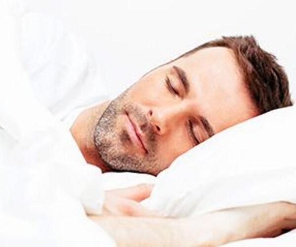 man asleep in bed with white sheets and pillow