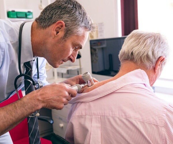 Dermatologist examining senior patient with dermatoscopy