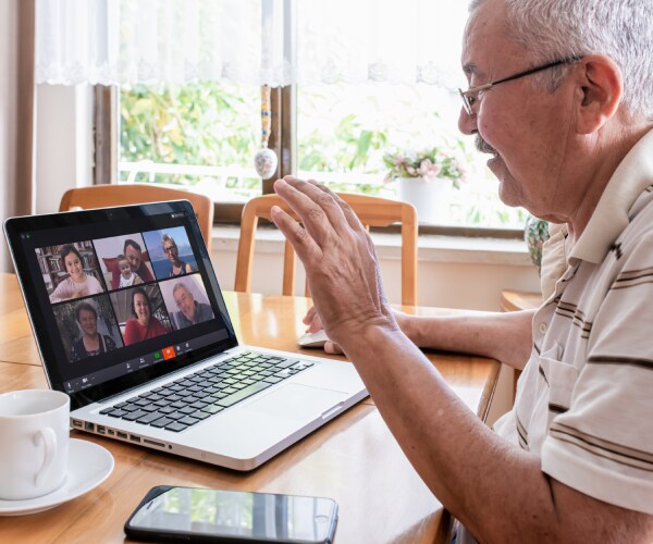 a man sitting at a computer meeting with people over zoom