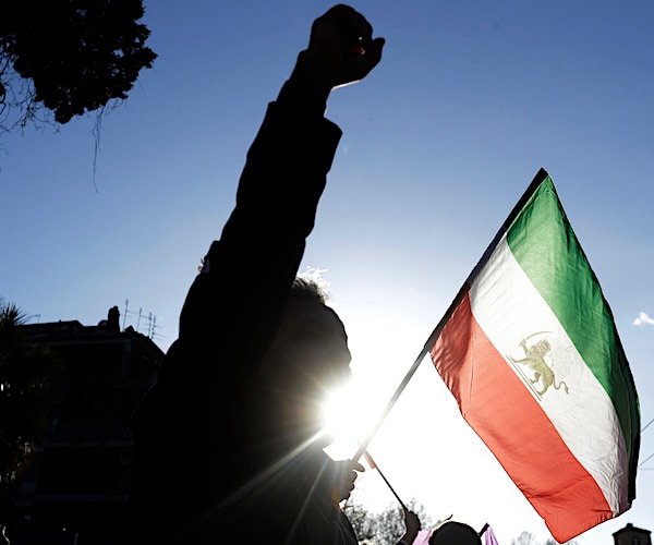 shadows of iran protesters waiving an iranian flag