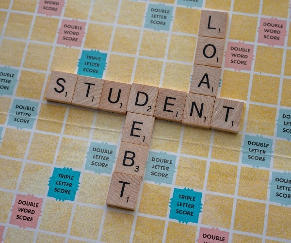 the words student loan debt written on a scrabble board