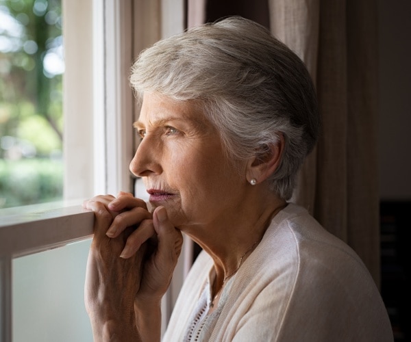 an older woman looking sadly out window