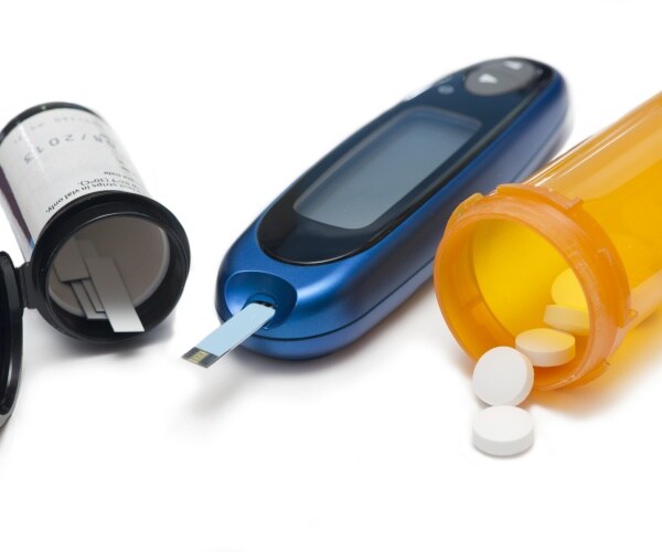 prescription bottle with pills spilling out, glucose monitor