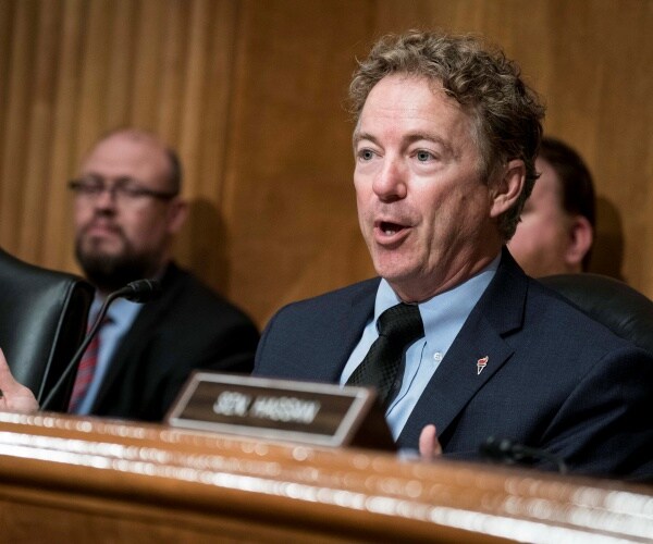 paul in a suit and black tie speaking at a hearing