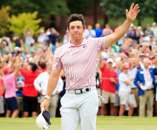 the golfer raises his hand to fans after winning 