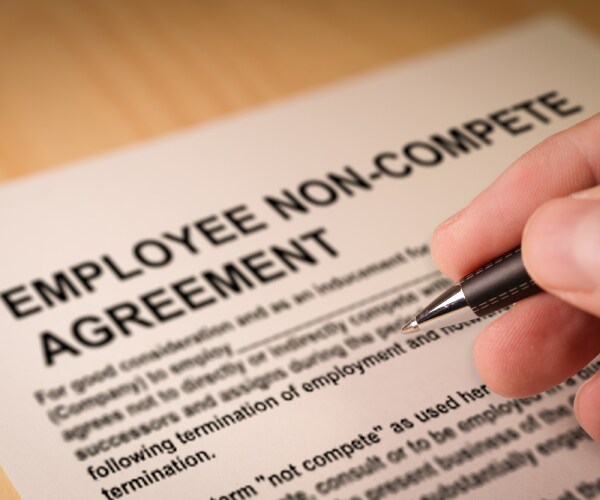 a hand signing a noncompete agreement