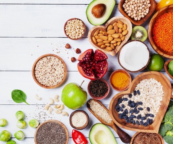 healthy foods including nuts fruit and grains are shown on a white table