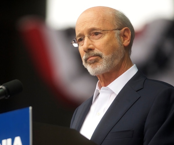 wolf in a suit and white dress shirt speaking at a podium