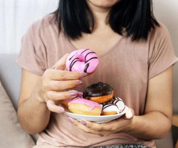 woman holding several frosted donuts