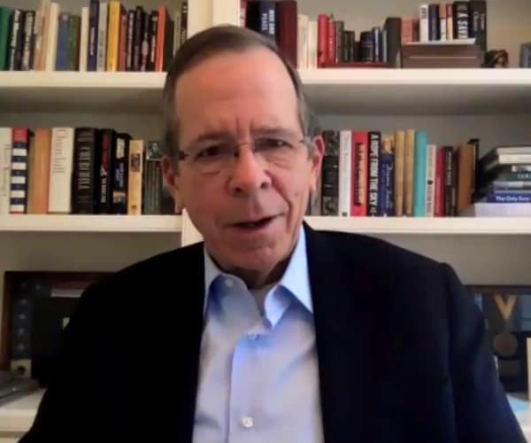 mike mullen sits in front of a bookcase