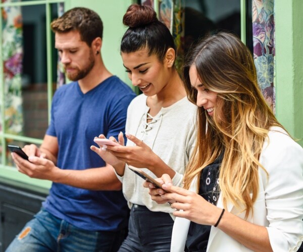 young adults all looking down at their phones