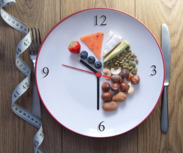 plate with food illustrating a clock and restricted intermittent fasting to certain times