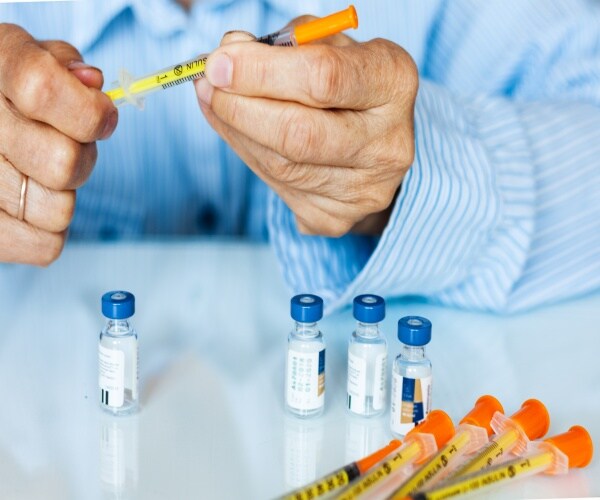 an older person's hands preparing to give themselves a shot for diabetes