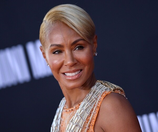 jada pinkett smith stands on red carpet