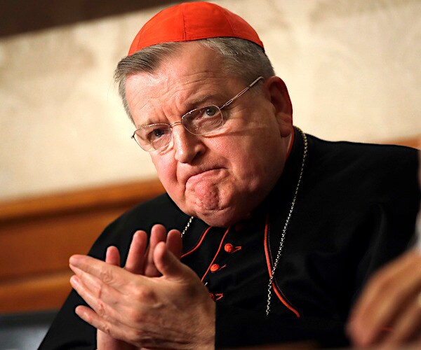 Cardinal Raymond Burke applauds while listening to a message