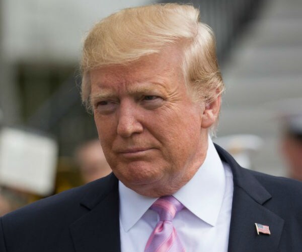 president donald trump wearing a suit, pink time and american flag pin on his left lapel