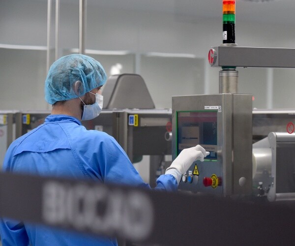 man in blue protective suit works in a biotech lab