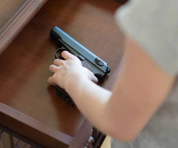 child's hand holding a gun