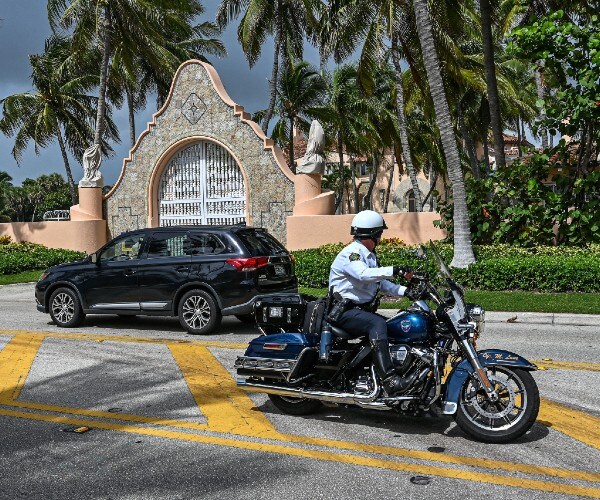 the front gate of mar a lago with police driving by