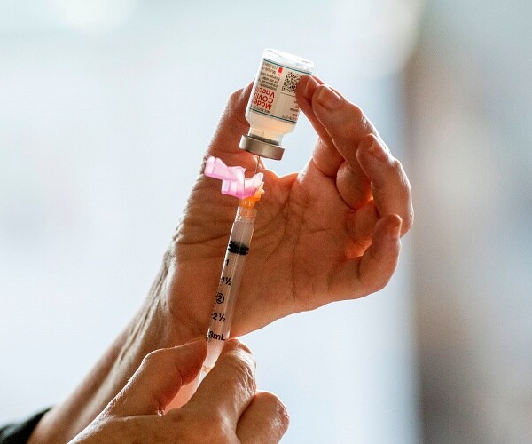 woman fills syringe with coronavirus vaccine