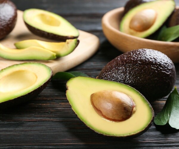 several avocados, cut open avocados, on table