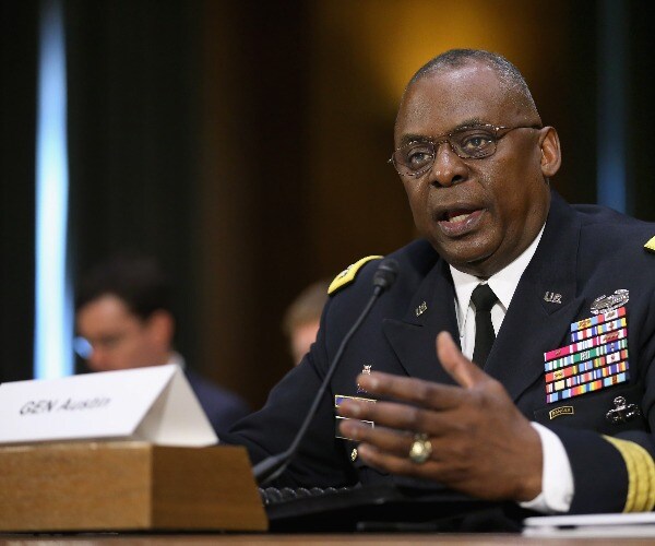 austin in uniform speaks at a hearing with a nameplate in front of him